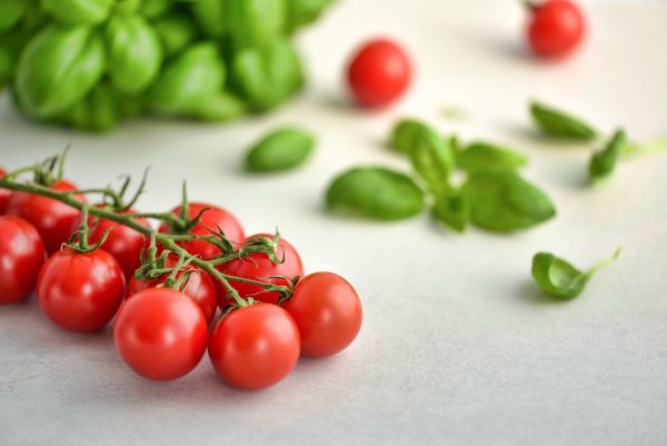 Rote Tomaten auf einem Holztisch – Italienisch lernen leicht gemacht mit Ich-Nix-Verstehen.de. Das Wort Tomate heißt auf Italienisch Pomodoro.